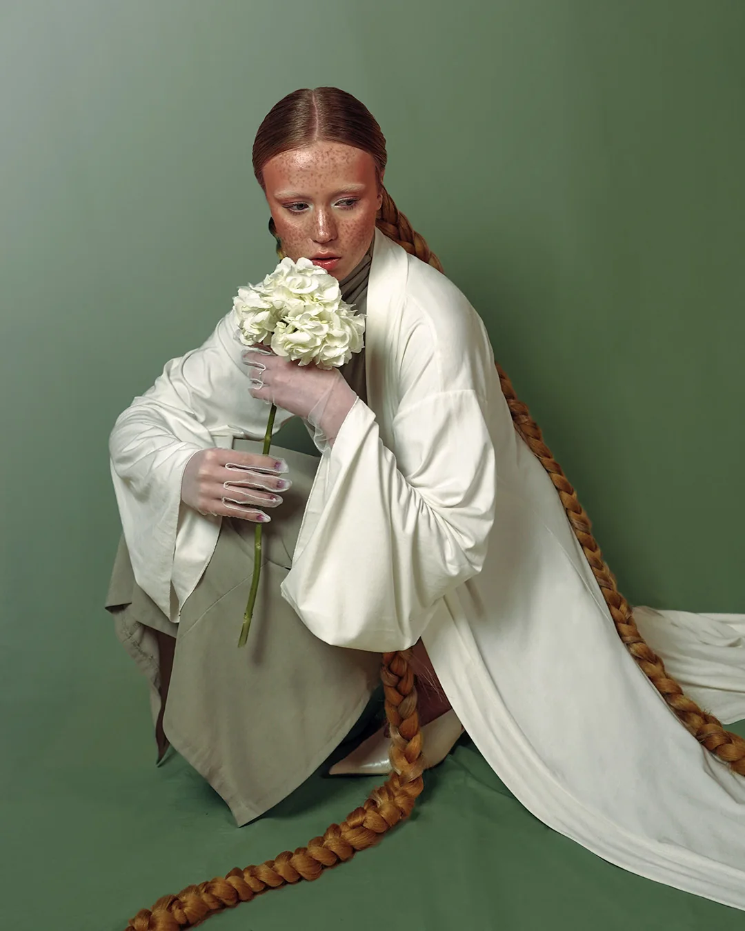 Seated portrait in cream robes holding flowers