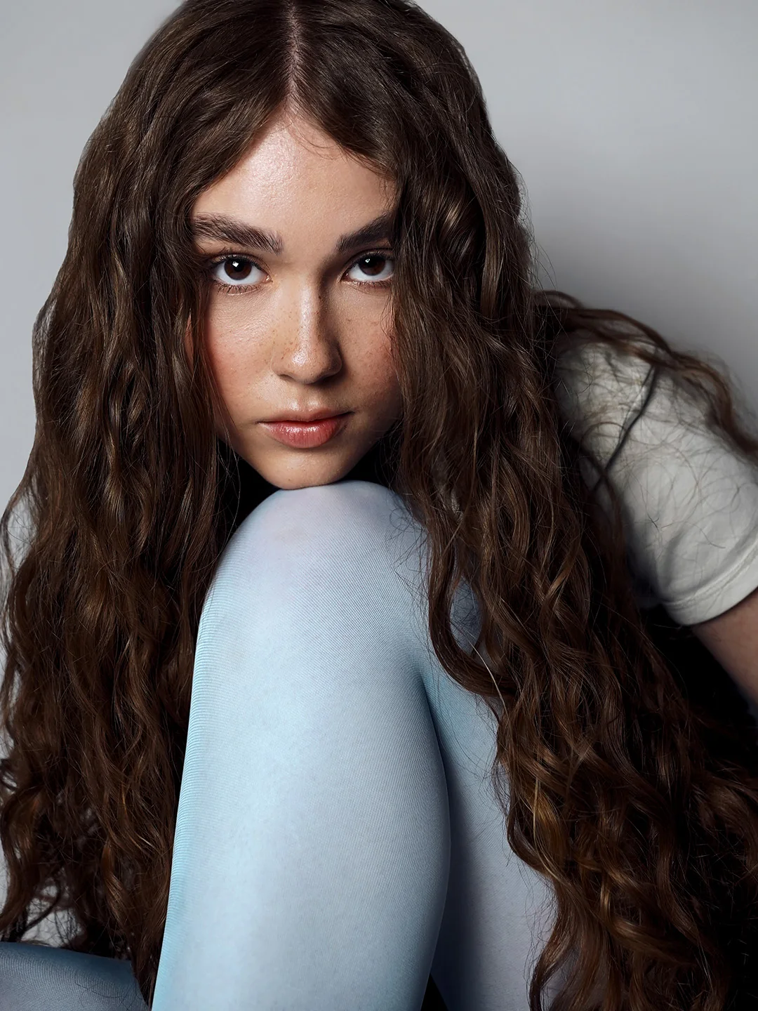 Portrait in pale blue tights, chin on knee