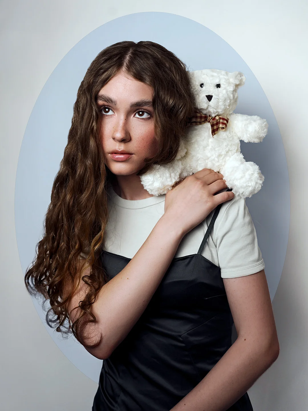 Portrait with a white teddy bear against a blue arch